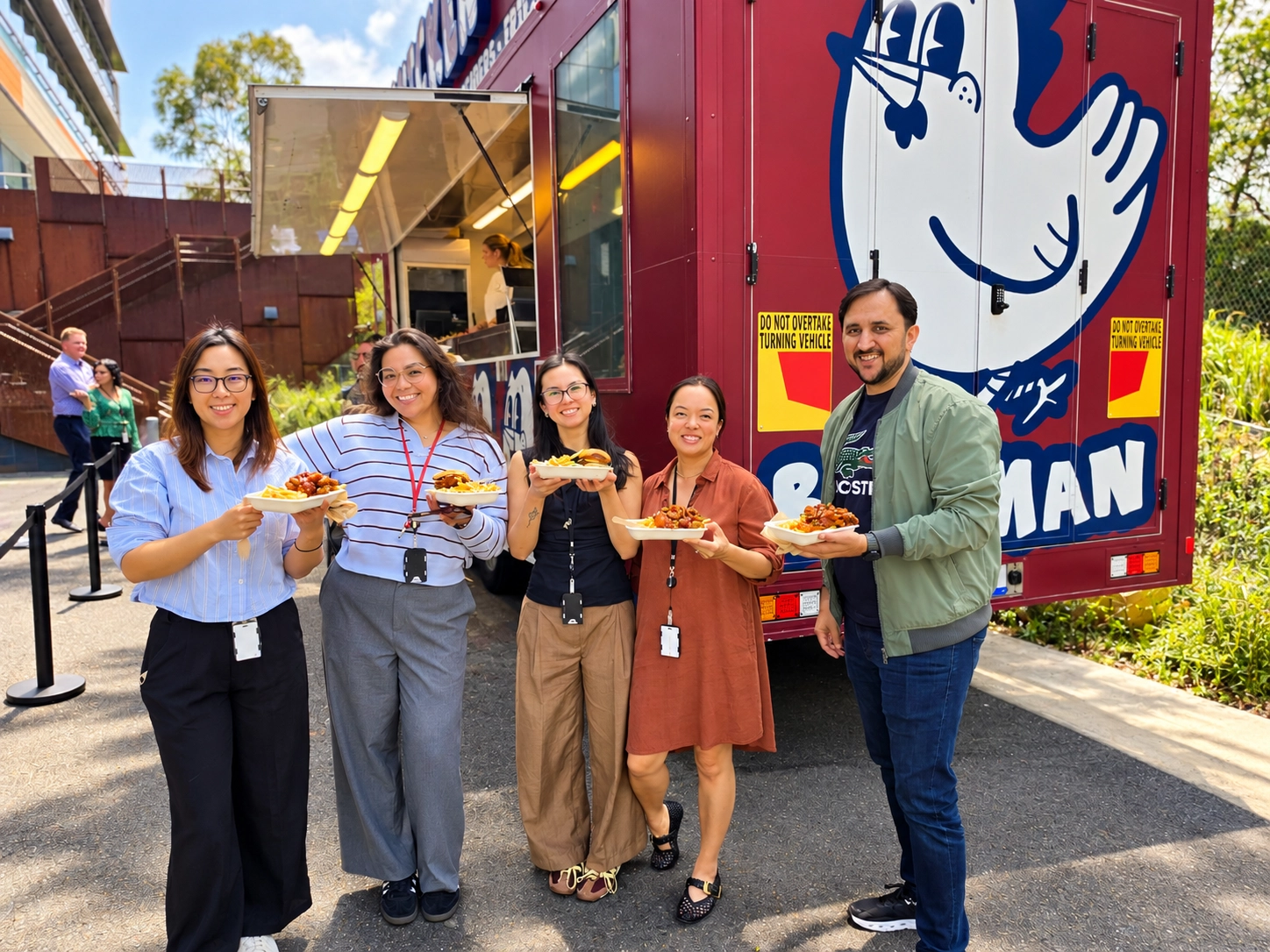 Samsung staff holding Birdman burgers and fried chicken beside the Birdman food truck
