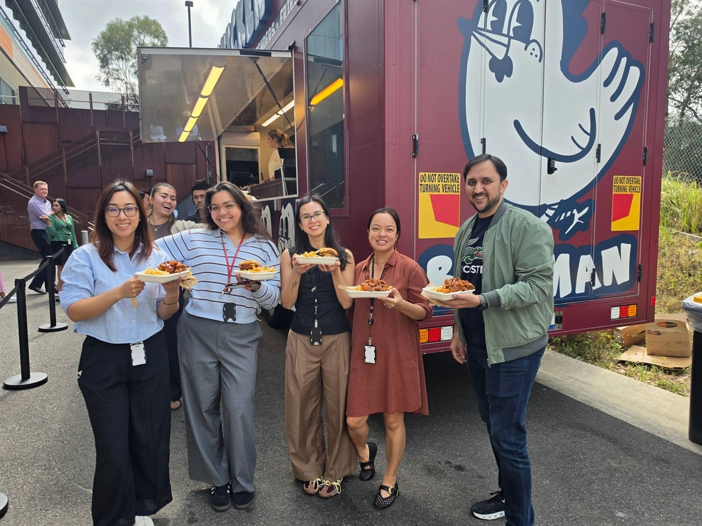 Samsung team members holding plates of Korean fried chicken, burgers and fries in front of the Birdman truck
